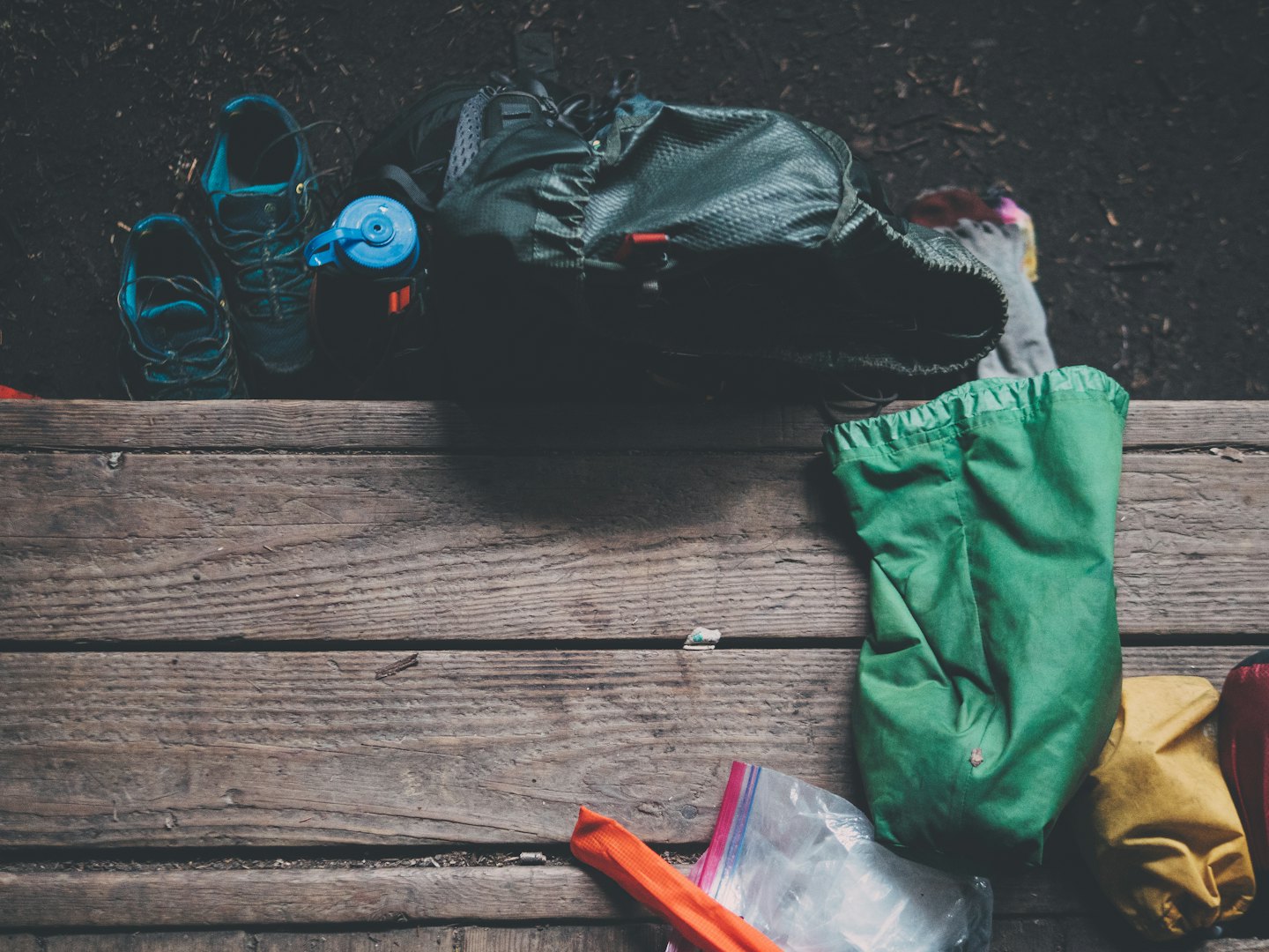 Wanderschuhe, Rucksack und Campingausrüstung auf Holz.